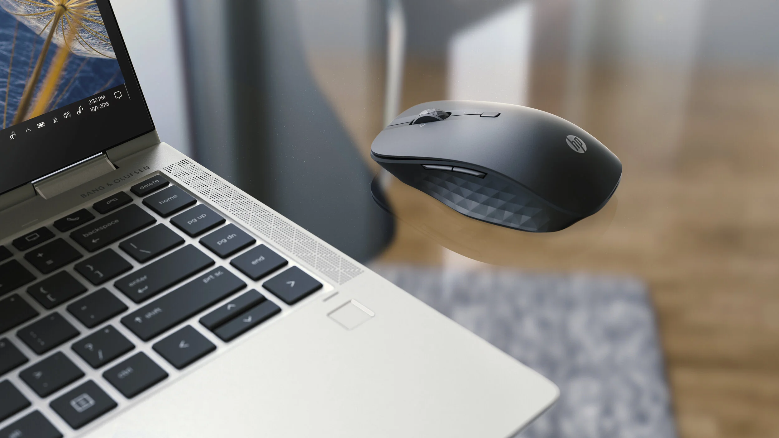 Black wireless mouse floating beside a silver laptop