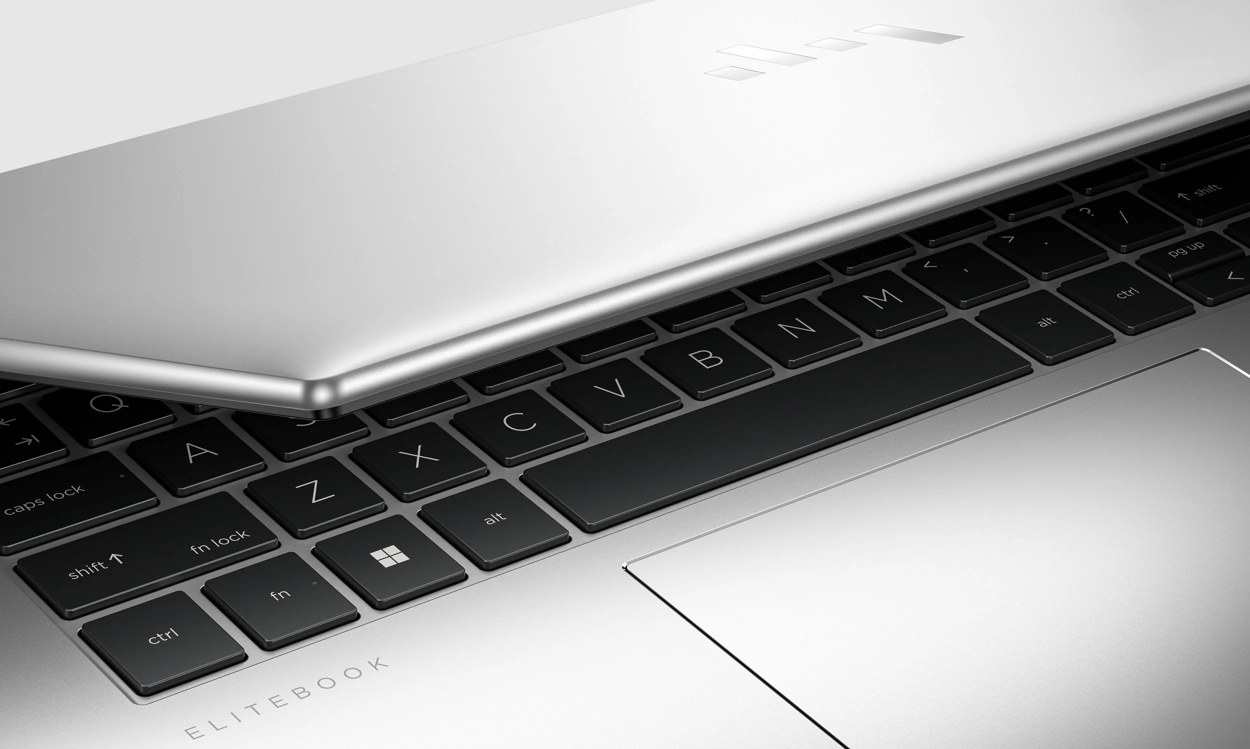 Closed silver laptop hovering above its black keyboard